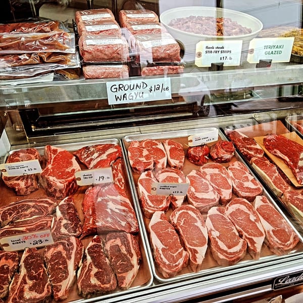 A Village Butcher and Market display case filled with various cuts of fresh beef and Wagyu ground meat.